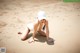 A woman in a white bikini and a baseball cap on the beach.