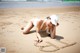 A woman laying on the beach writing in the sand.