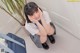 A young woman in a school uniform sitting on the floor.