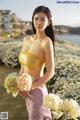 A woman in a yellow top holding a bunch of flowers.