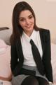 A woman in a business suit sitting on a bed.