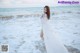A woman in a white dress standing in the ocean.