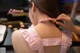 A woman in a pink and white checkered dress is putting on a pink collar.